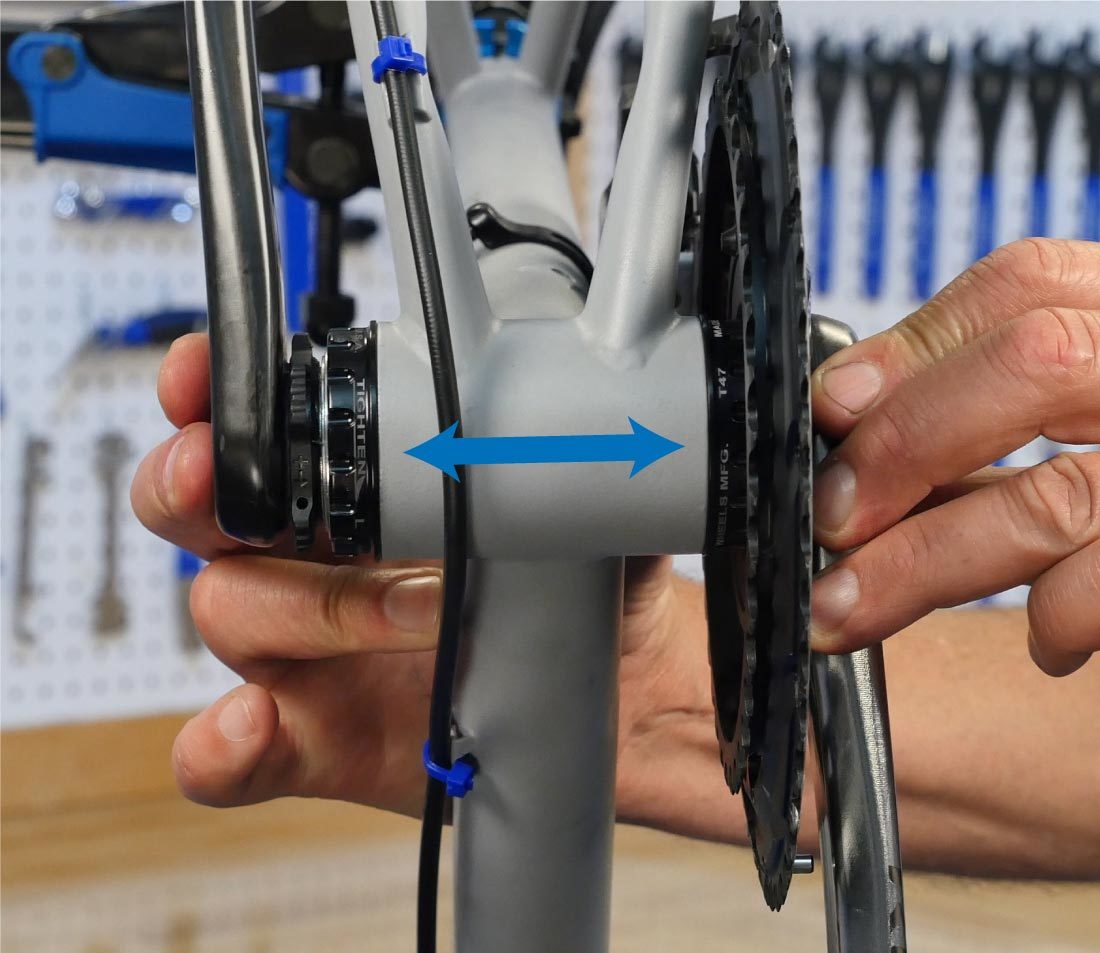 View of crankset from bottom bracket shell underside, with arrows indicating side-to-side movement