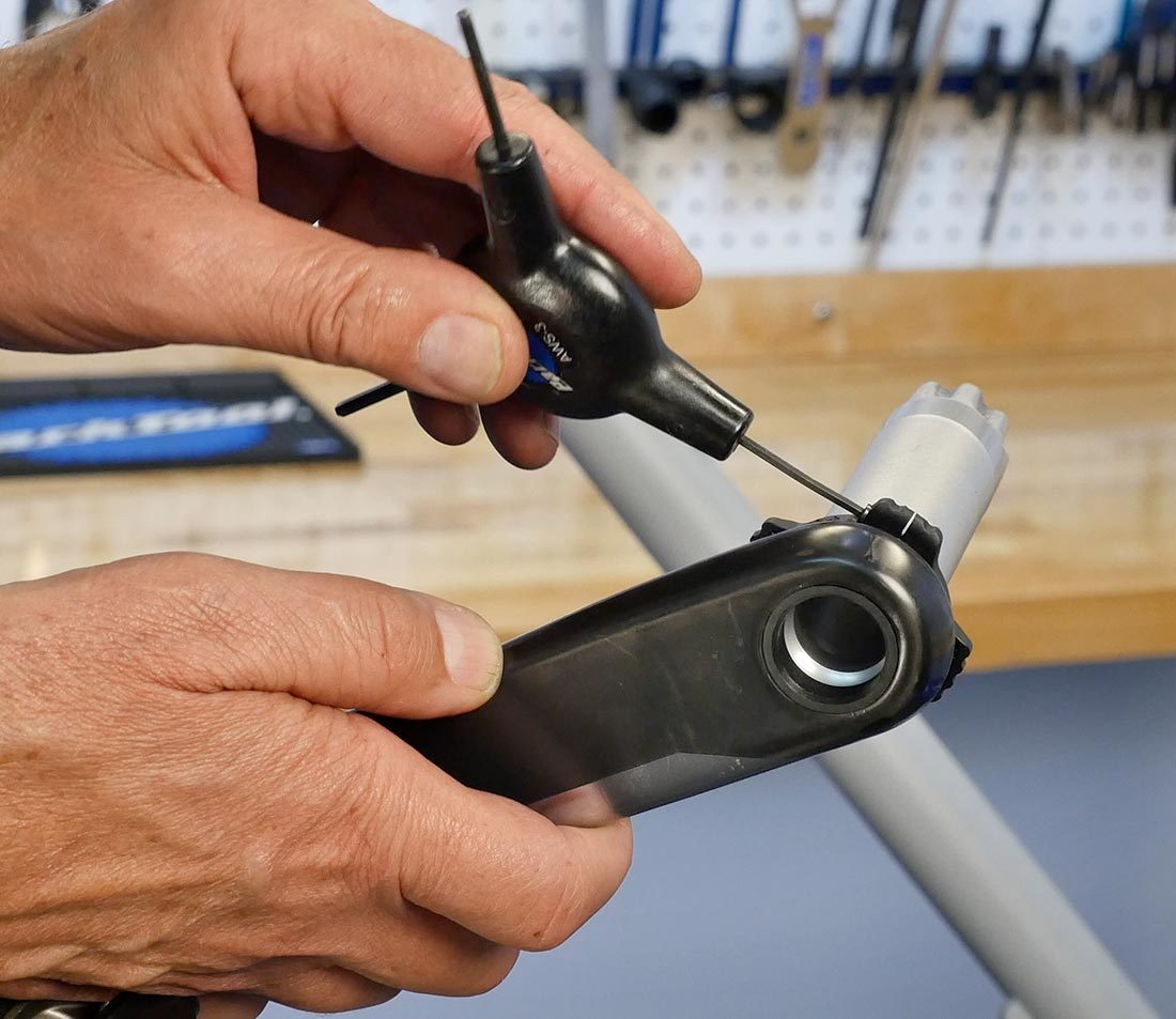 Holding non-drive side crank arm while hand loosening preload ring pinch bolt using small AWS-3 hex wrench