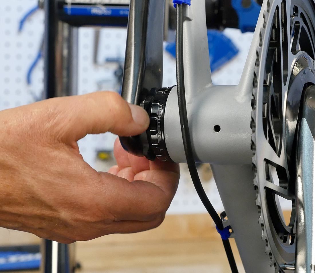 Hand pushing preload ring against non-drive side bearing installed in bottom bracket shell