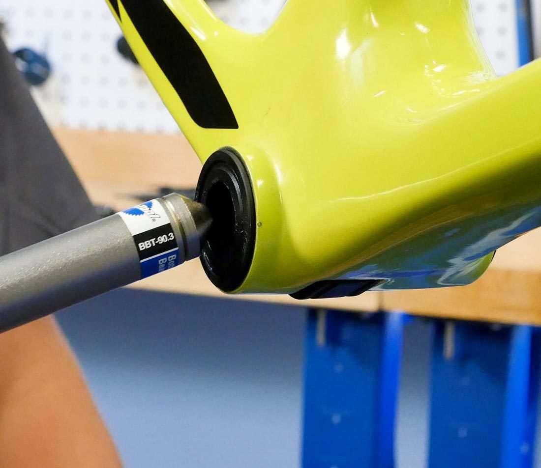 Small end of the BBT-90.3 being inserted into press fit bottom bracket cup on yellow bicycle frame