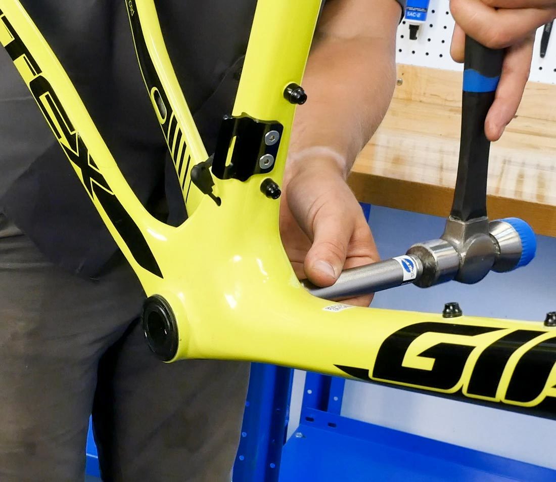 Striking the small end of the BBT-90.3 driver to remove press fit cup from bottom bracket shell on yellow bike