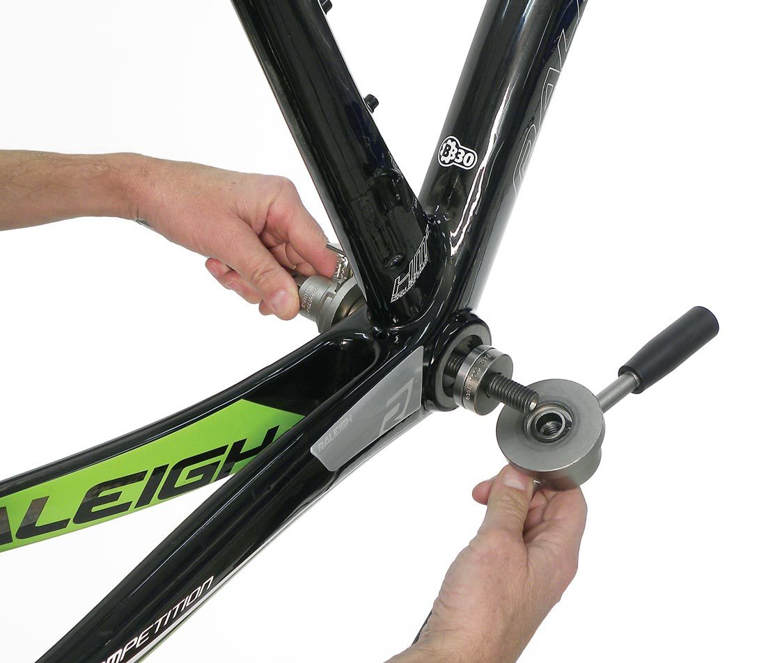 Bearing cup press inserted into bottom bracket shell with bearing and drift on threaded stud for installation