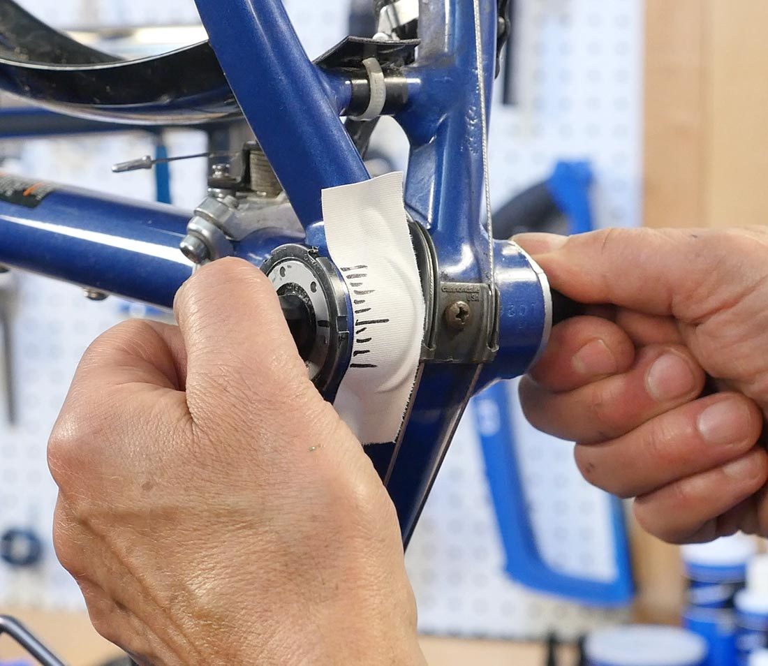 Hands turning spindle in bottom bracket to check for play after adjustment