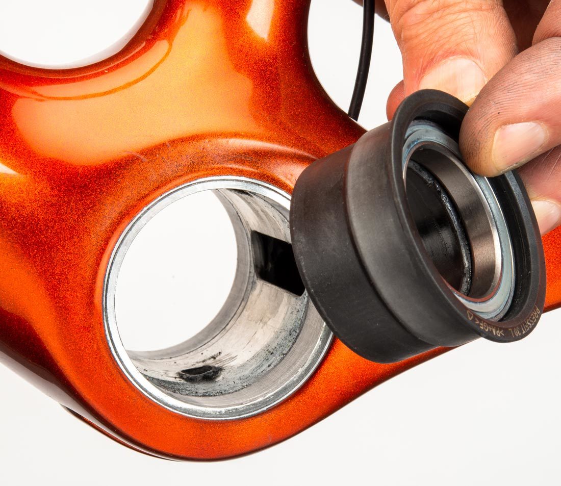 PF46 bearing adaptor held next to compatible bottom bracket shell of orange bicycle frame