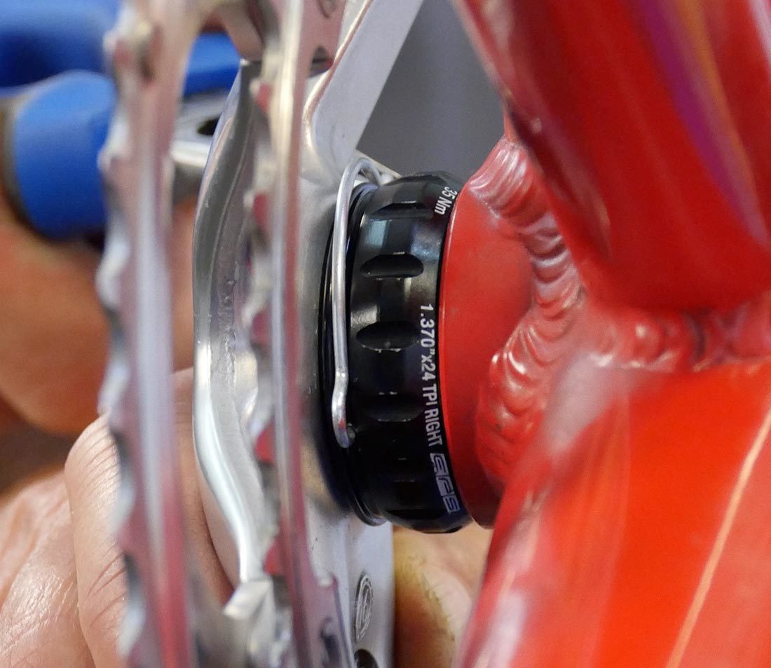 Closeup of needle-nose pliers removing retaining clip from external cup of Campagnolo® Ultra-Torque® system