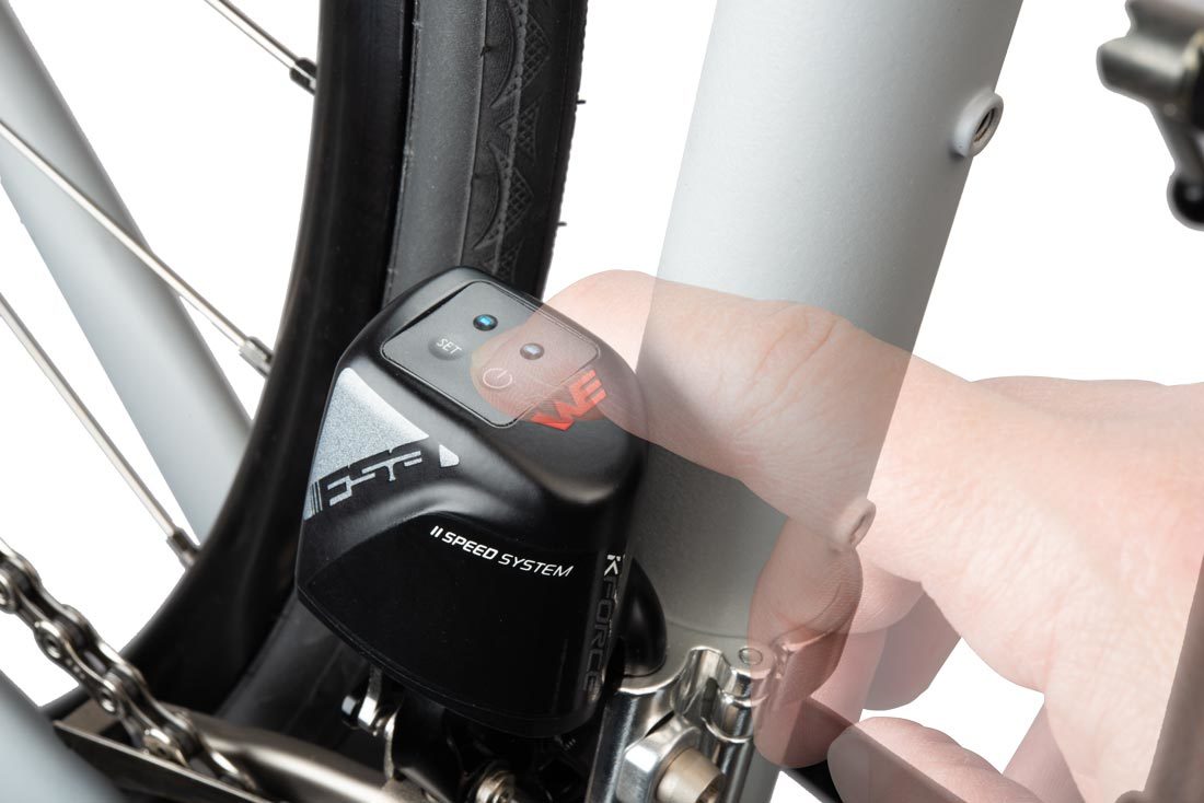 Finger pressing the power button on WE® front derailleur mounted to bicycle, with lights illuminated