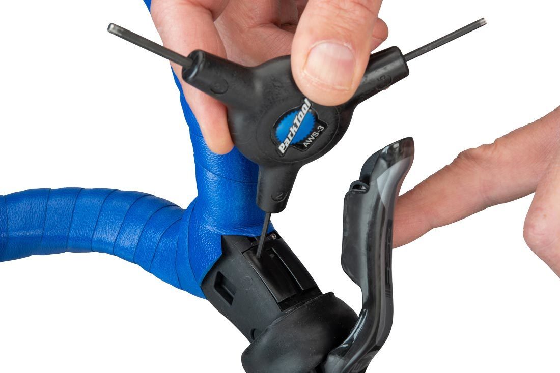 Button being pressed on WE® brake/shift lever using small wrench on AWS-3