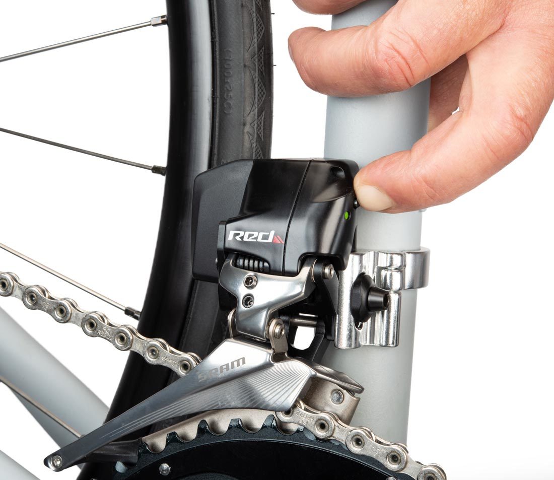 Finger pressing button on front AXS® derailleur mounted on a bicycle