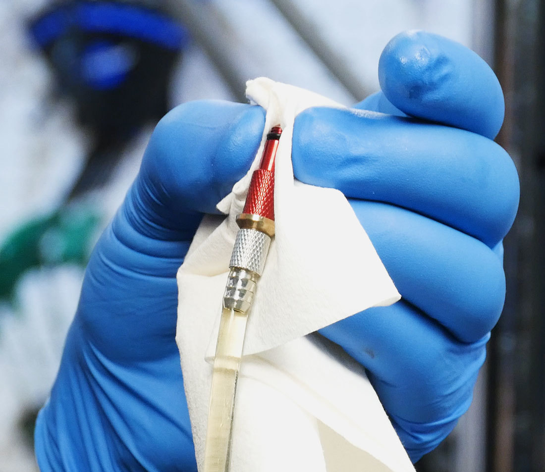 Rag being held against syringe hose end while pushing out air bubbles