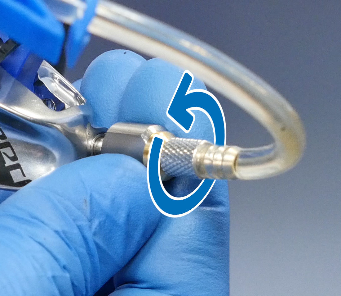 Bleeding Edge adaptor being held and rotated counterclockwise to loosen port on brake caliper