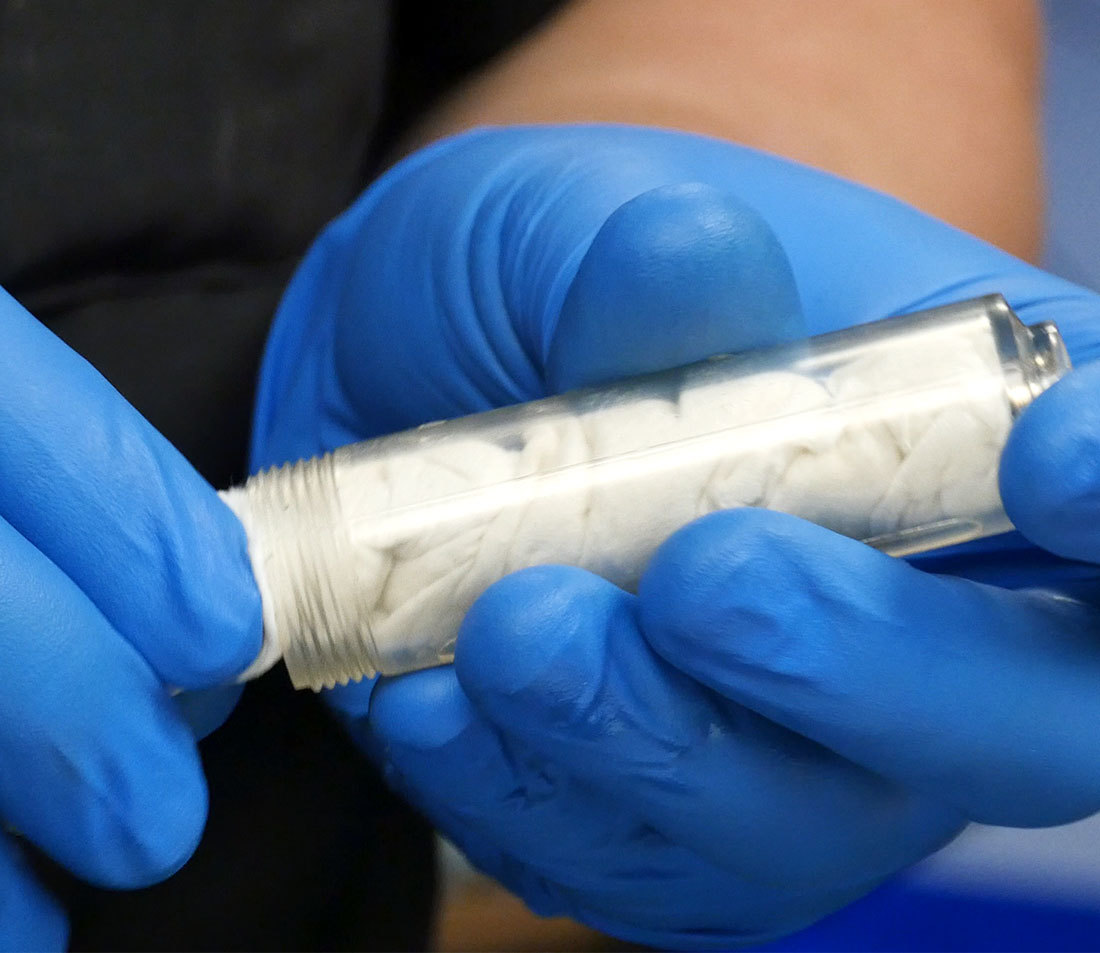 Bleed syringe with plunger removed, with clean rag inserted into the body for cleaning