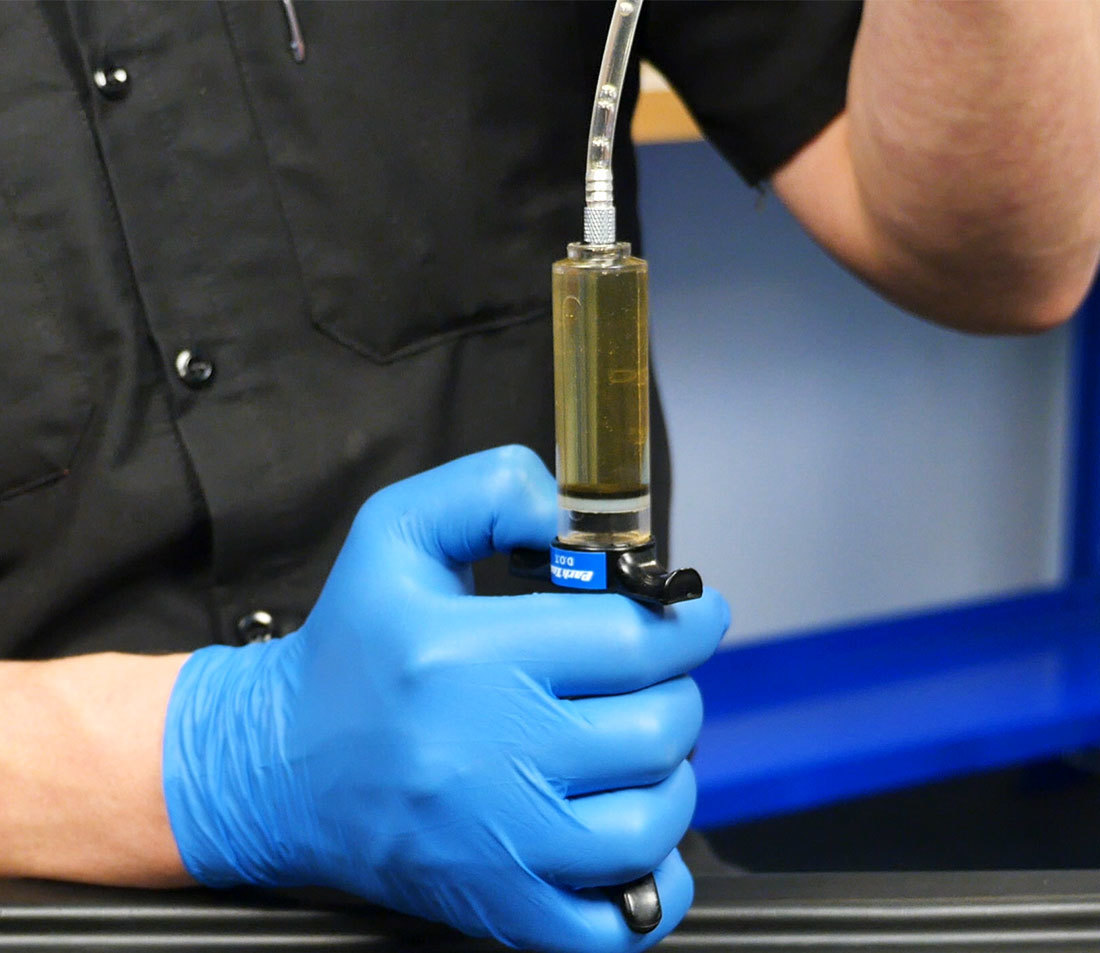 Syringe being held upside down with hose lifted up to allow bubbles to escape