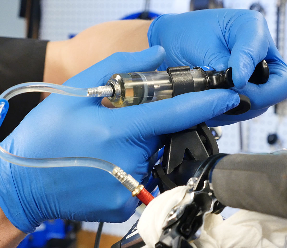 Bleed syringe being secured in syringe holder on flat handlbars