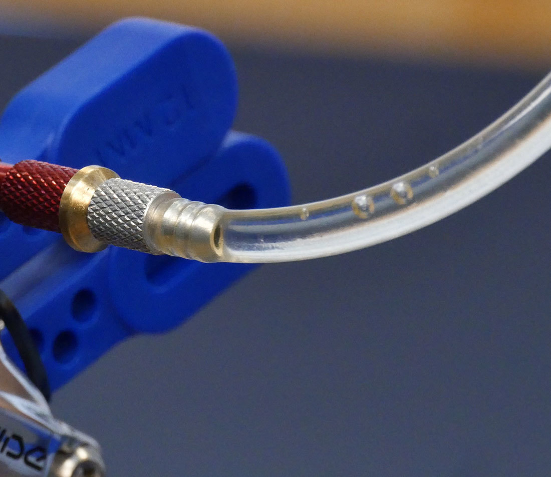 Closeup of bubbles in hose end at brake caliper bleed port