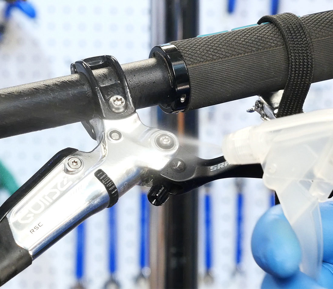 Brake lever being sprayed with rubbing alcohol, especially around bleed port