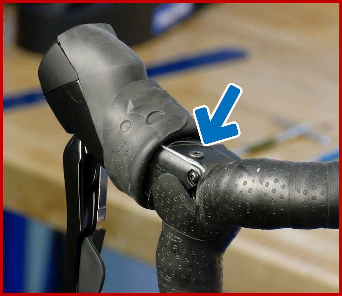 Shimano brake levers on drop handlebars with hood pulled back to expose back port for brake bleeding