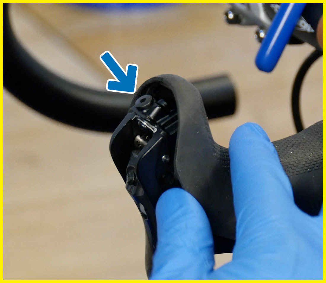 Shimano brake levers on drop handlebars with front of hood pulled back to expose front port for brake bleeding