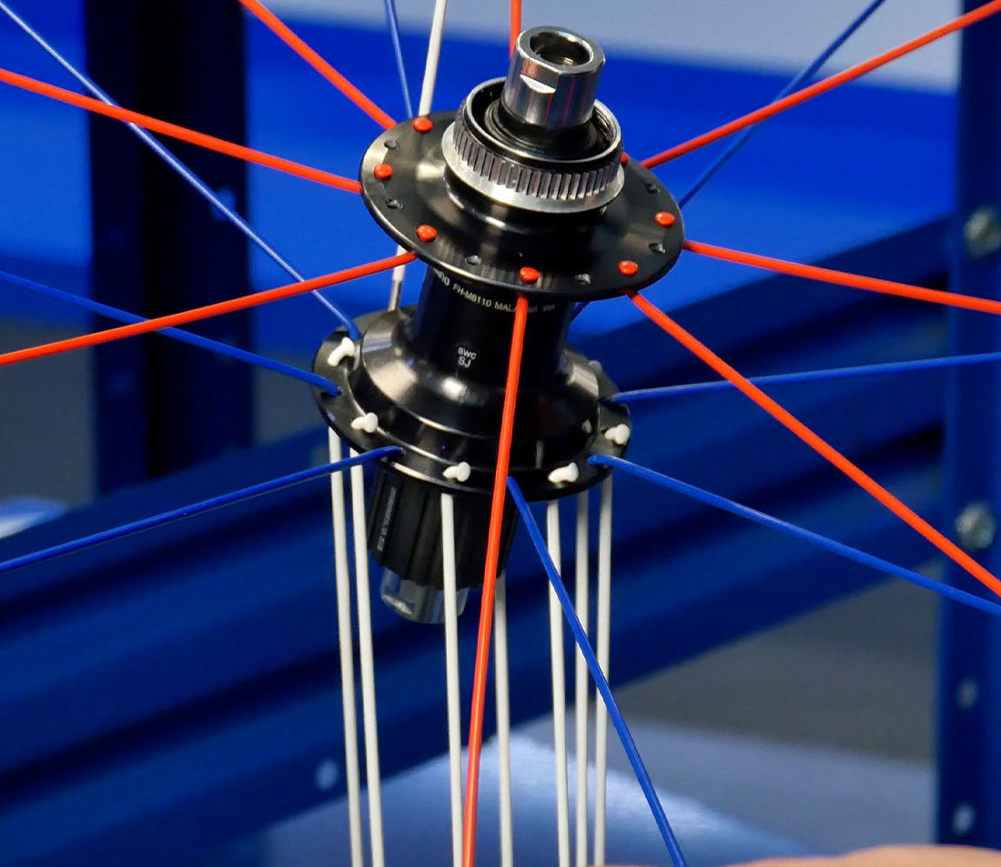 Partially assembled wheel with non-drive side up and third spoke set hanging from drive side hub flange