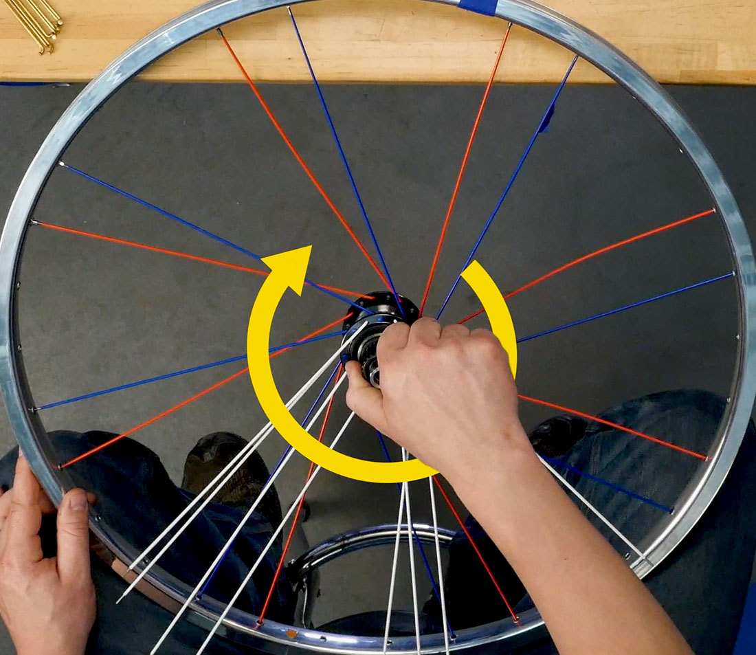 Hub of partially assembled wheel being twisted in clockwise motion