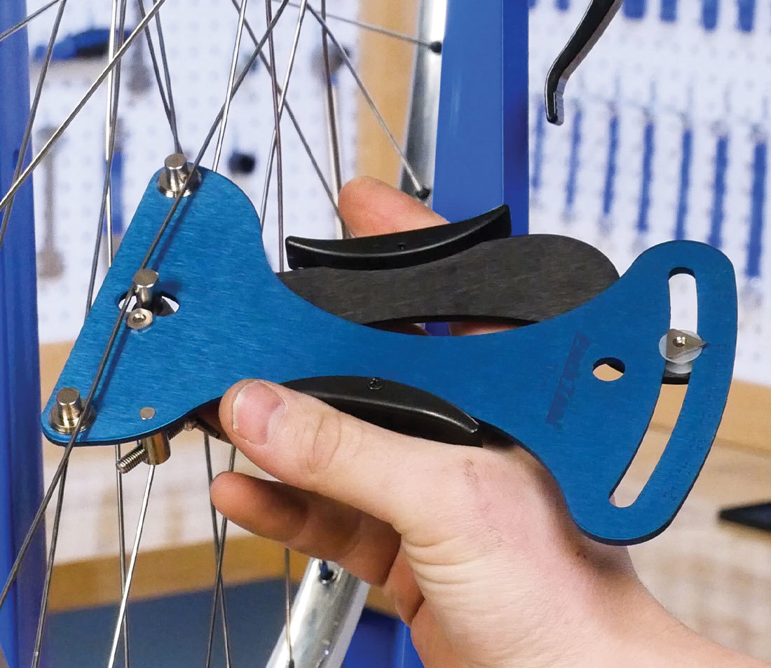 A bicycle spoke being meausured by a spoke tensiometer