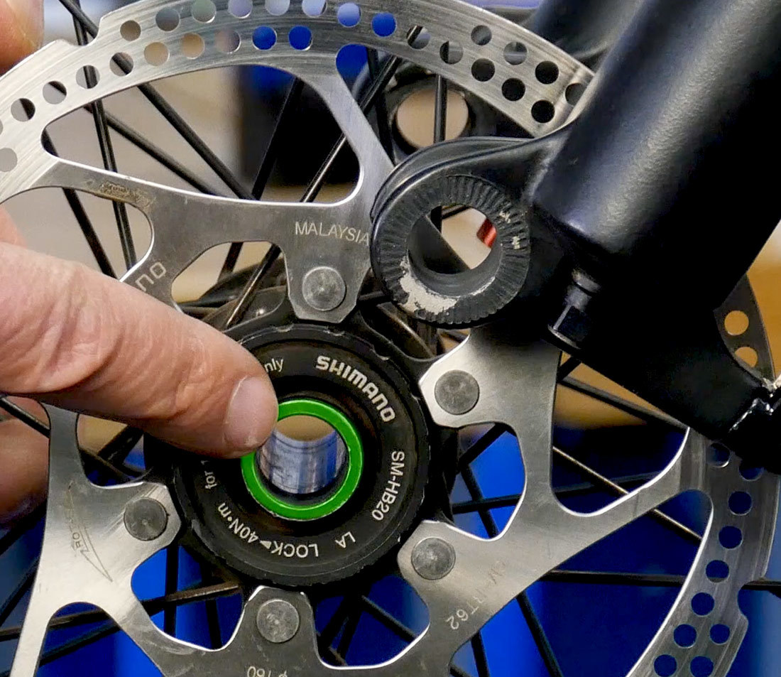 Thru-axle contact point on mountain bike wheel hub highlighted green for identification